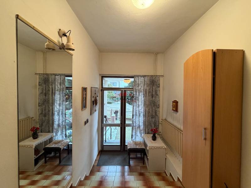 Családi ház belső tere tükörrel, szekrénnyel, padlóburkolattal és kilátással a kertre.