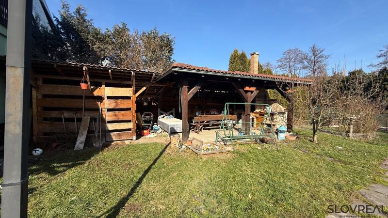 A családi ház kertje Lutilán, fa pavilonnal és hintával a telken.