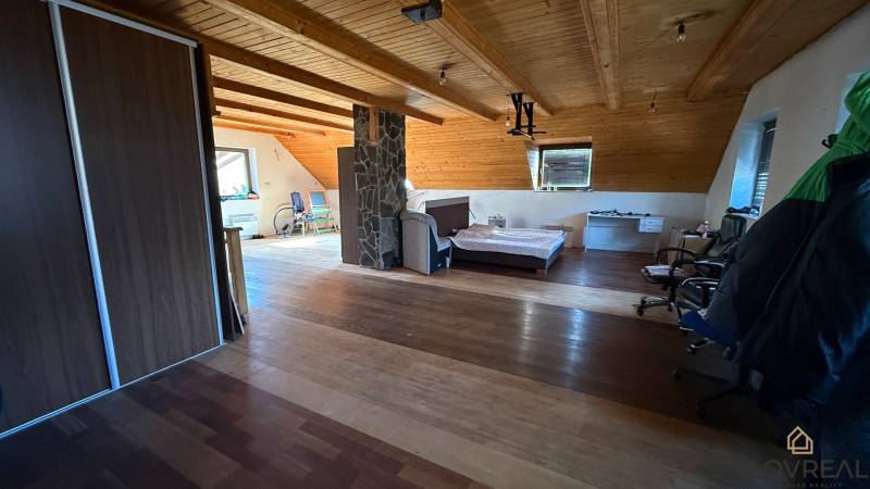 Tetőtéri szoba ággyal, szekrénnyel és fa dekorációjú padlóval egy családi házban.