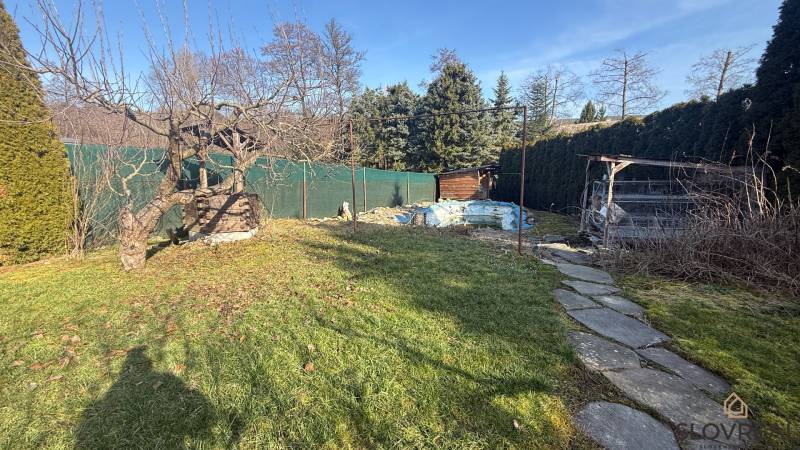 Családi ház kertje Lutilában fákkal és sétánnyal napos környezetben.