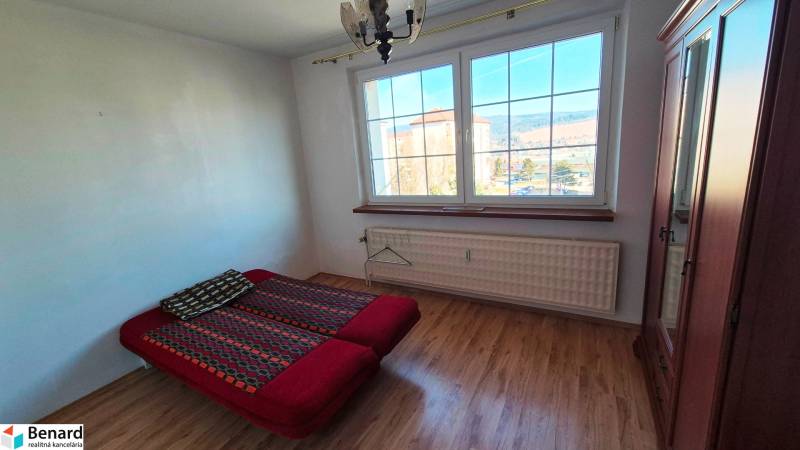 Hálószoba ággyal, szekrénnyel és fa dekorációjú padlóval egy kétszobás lakásban.