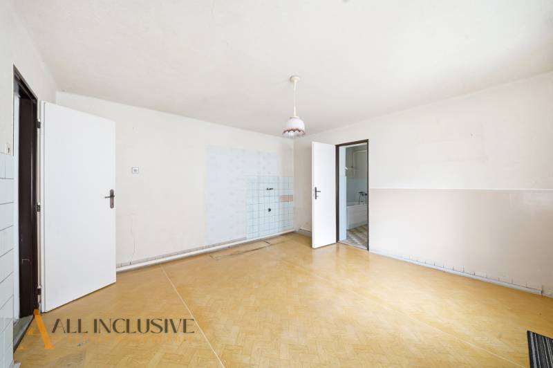 Tágas szoba egy családi házban, fa dekorációjú padlóval és egyszerű világítással.