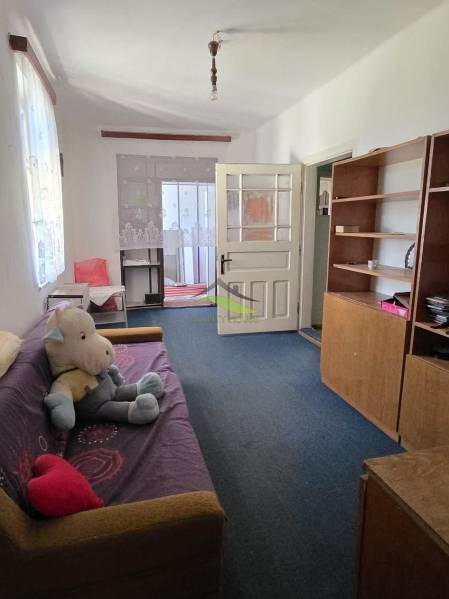 Nappali egy családi házban kanapéval, polcos szekrénnyel és játékkal a padlón.