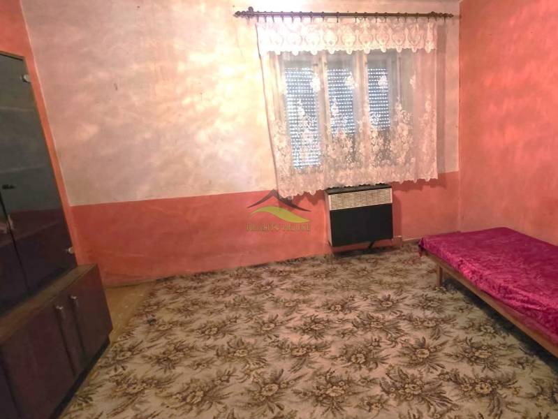 Szoba családi házban szőnyeggel, ággyal és szekrénnyel, függönnyel az ablakon.