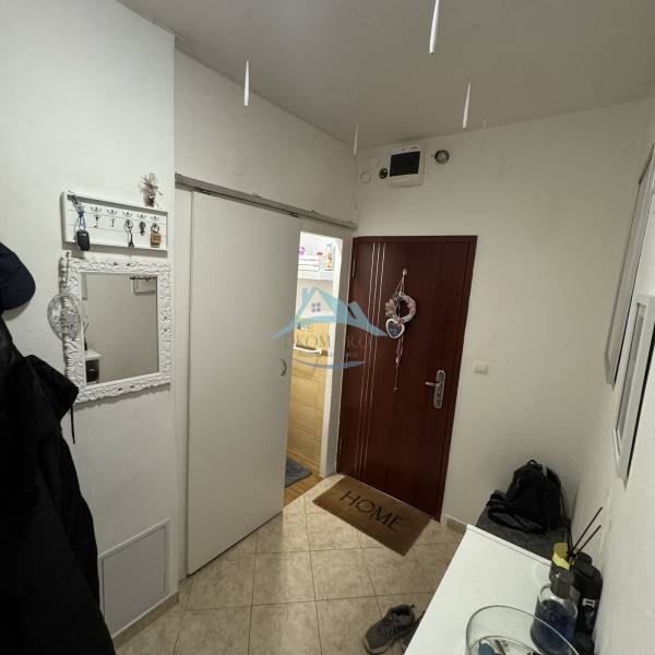 Előszoba egy 3 szobás lakásban fogasokkal, tükörrel és bejárati ajtóval.