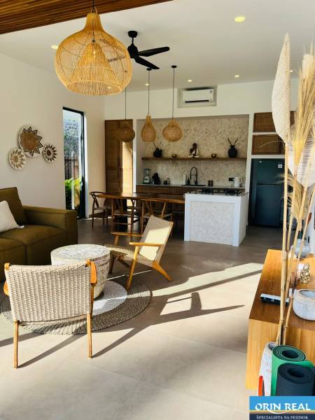 Családi ház belső tere fonott kiegészítőkkel és konyhával, fa dekorációjú padlóval.