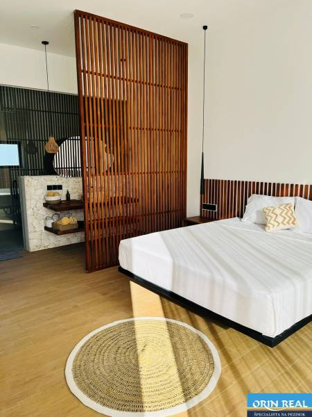 Hálószoba családi házban fa dekor padlóval, fa válaszfallal és kör alakú szőnyeggel.