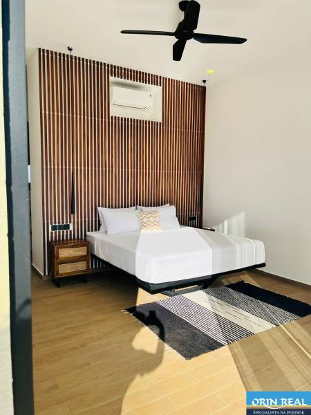 Hálószoba családi házban mintás fallal, ventilátorral, szőnyeggel és fa dekorációjú padlóval.