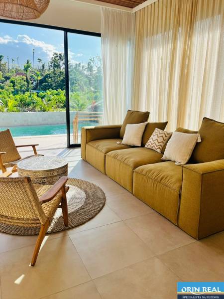 Családi ház nappalija nagy ablakkal, kilátással a kertre és a medencére.