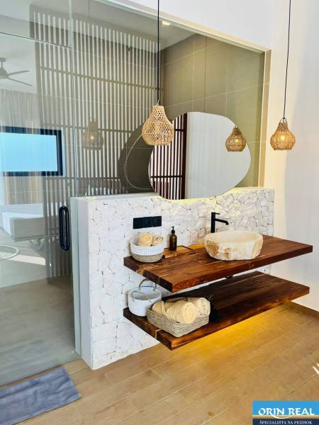 Fürdőszoba egy családi házban, mosdókagylóval egy fa polcon és fa dekorációjú padlóval.