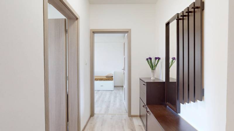 Folyosó egy 2 szobás lakásban fa dekor padlóval és sötét bútorokkal.