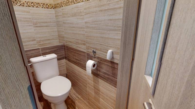 Fürdőszoba fa dekorációjú falakkal egy kétszobás lakásban.