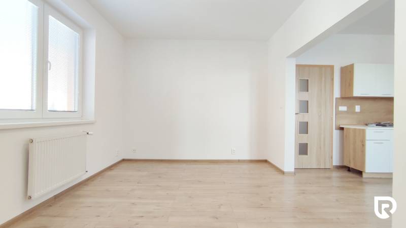 Nappali egy kétszobás lakásban fa dekor padlóval és konyhasarokkal.