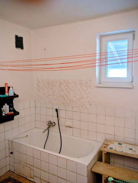 Fürdőszoba családi házban káddal, polccal és fehér csempékkel.