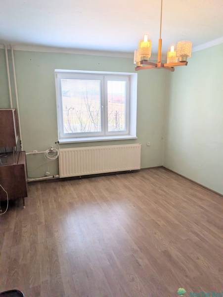 Szoba családi házban fa dekoros padlóval és ablakkal, radiátorral.