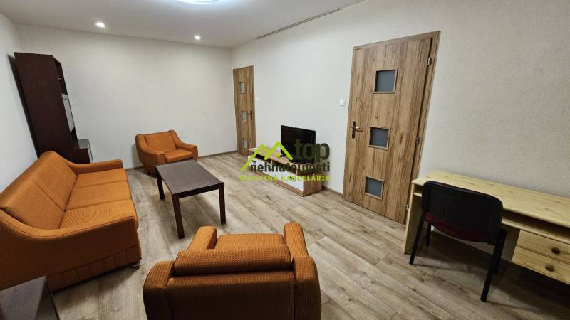 Nappali egy kétszobás lakásban narancssárga bútorokkal és fa dekorációjú padlóval.