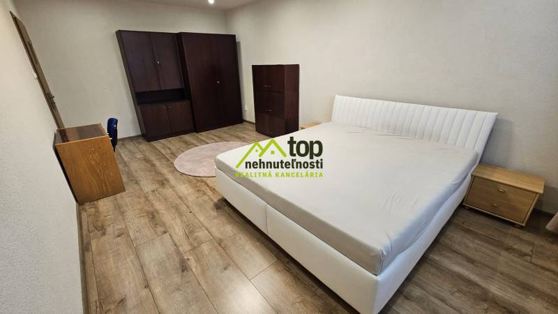 Hálószoba egy kétszobás lakásban ággyal, szekrénnyel és fa dekorációjú padlóval.