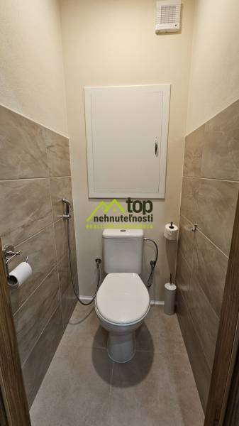 Csempeburkolatú és kerámia WC-vel ellátott WC egy kétszobás lakásban.