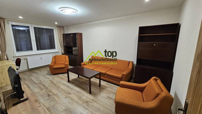 Nappali egy kétszobás lakásban narancssárga kanapékkal és fa mintázatú padlóval.