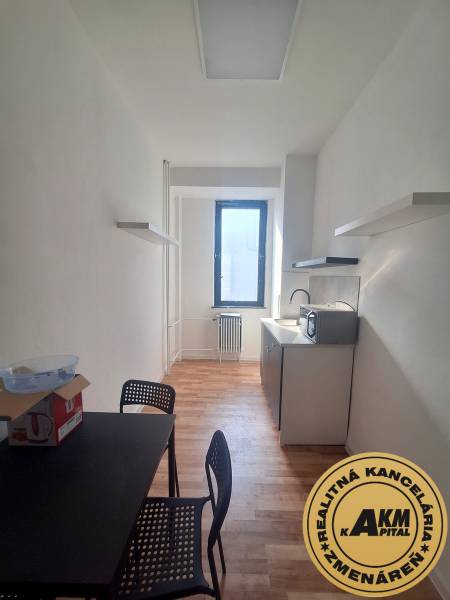 Keskeny iroda fekete asztallal, székekkel és fa dekorációjú padlóval.