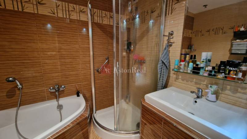 Fürdőszoba egy háromszobás lakásban káddal, zuhanyzóval és mosdóval.