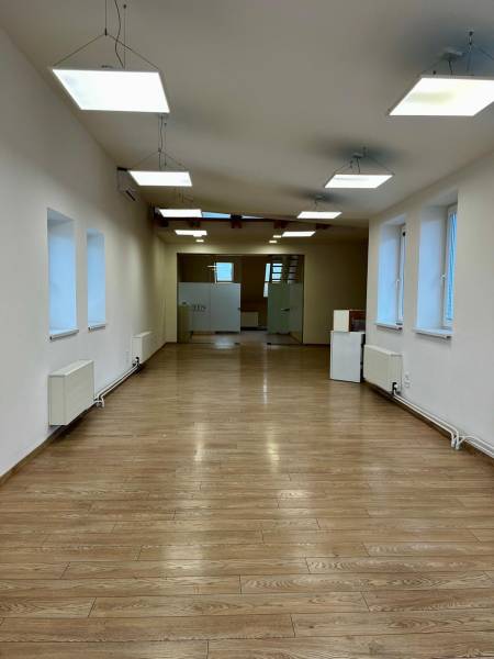 Irodák belső tere fa dekor padlóval és függő lámpákkal.