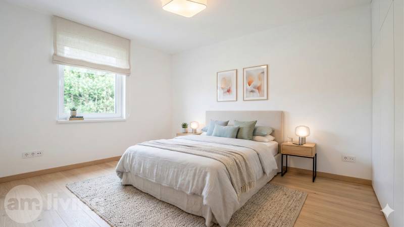 Világos hálószoba fa dekor padlóval, világos ágytakaróval ellátott ágy és képek a falon.