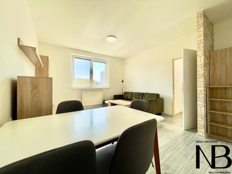 Nappali egy kétszobás lakásban fa mintázatú padlóval, kanapéval és étkezőasztallal.