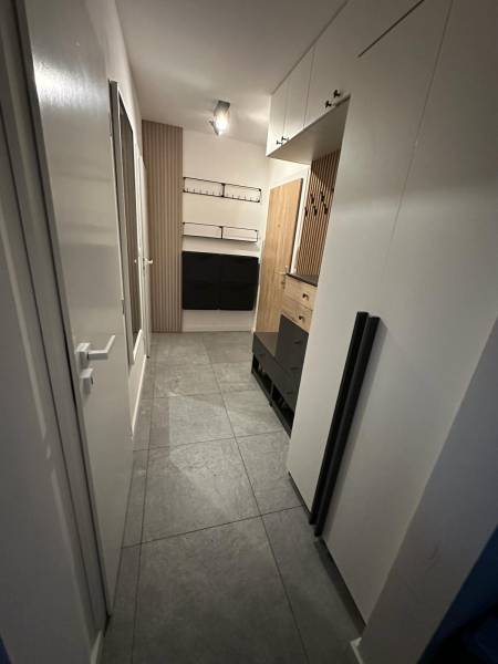 Folyosó egy kétszobás lakásban csempével, szekrényekkel és fa falpanelekkel.