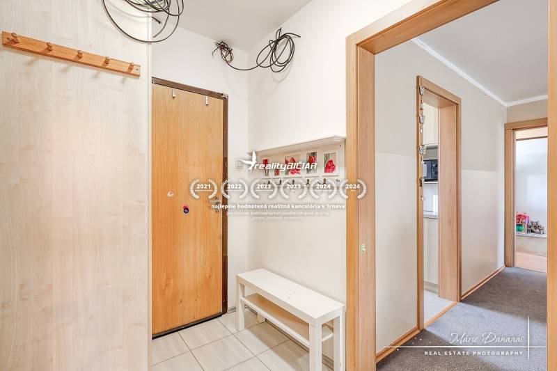 Négy szobás lakás előszobája, fehér falak, fogasok és pad.