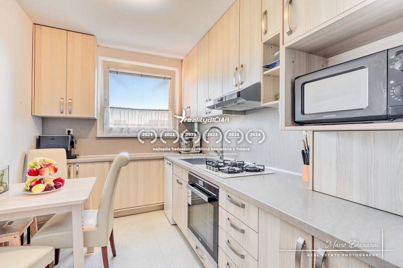 Konyha egy 4 szobás lakásban, gyümölcsökkel az asztalon és beépített készülékekkel.