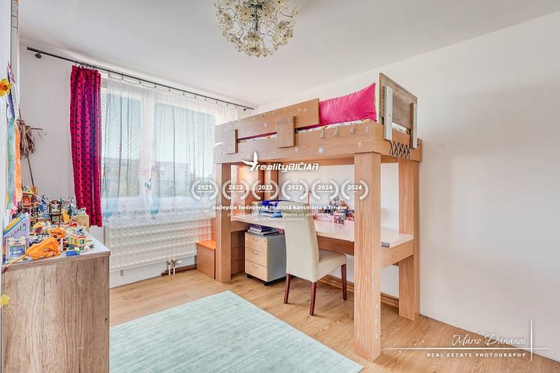 Gyerekszoba magasított ággyal, fa dekoros padlóval és játékokkal a polcokon.