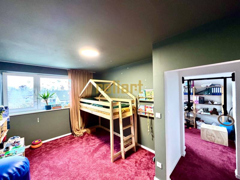 Gyerekszoba egy családi házban, fa ággyal és bordó szőnyeggel.