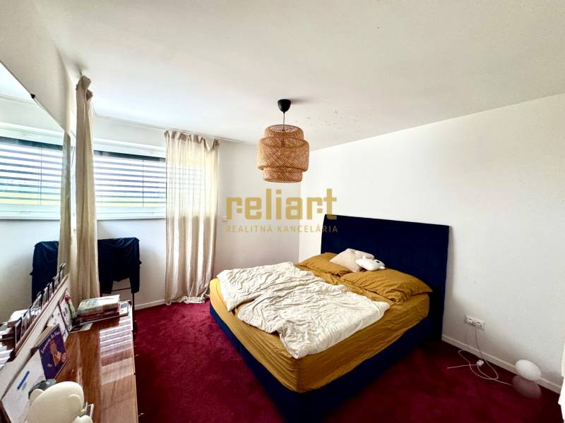 Hálószoba egy családi házban piros szőnyeggel, kék ággyal és nagy ablakkal.