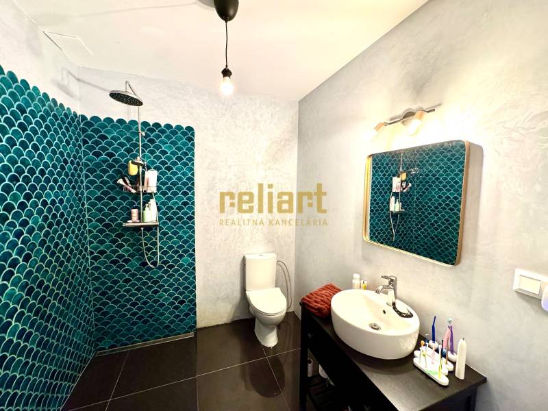 Fürdőszoba sötét padlóval és kék csempékkel egy családi házban.