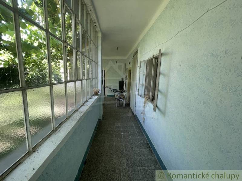 Keskeny üvegezett tér a családi házban, kilátással a kertre.