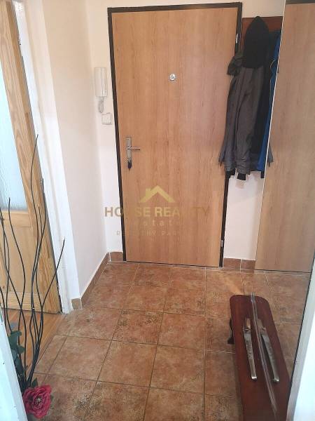 A kétszobás lakás előszobája kerámia padlóval és kabátokkal a fogason.