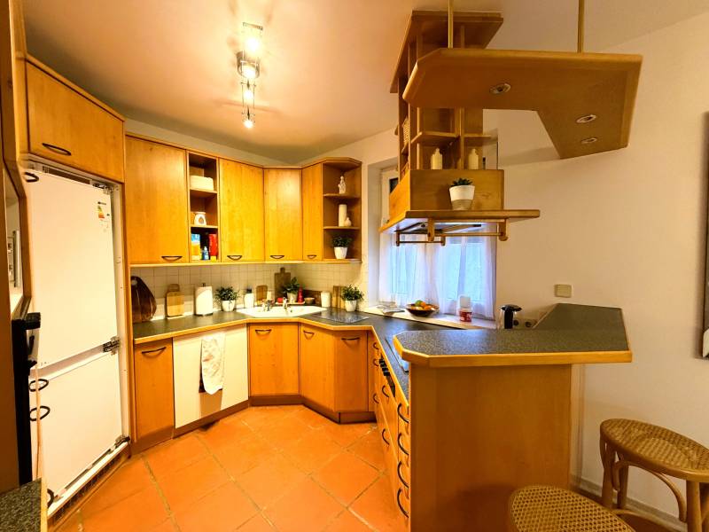 Konyha egy háromszobás lakásban fa szekrényekkel és bárpulttal.