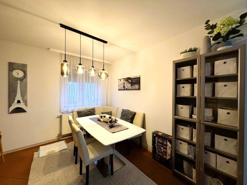 Ebédlő asztallal, székekkel és polccal egy 3 szobás lakásban dekoratív világítással.