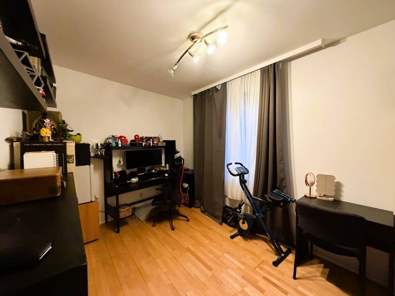 Szoba fa dekoros padlóval, íróasztal, számítógép, szobabicikli, polcok.