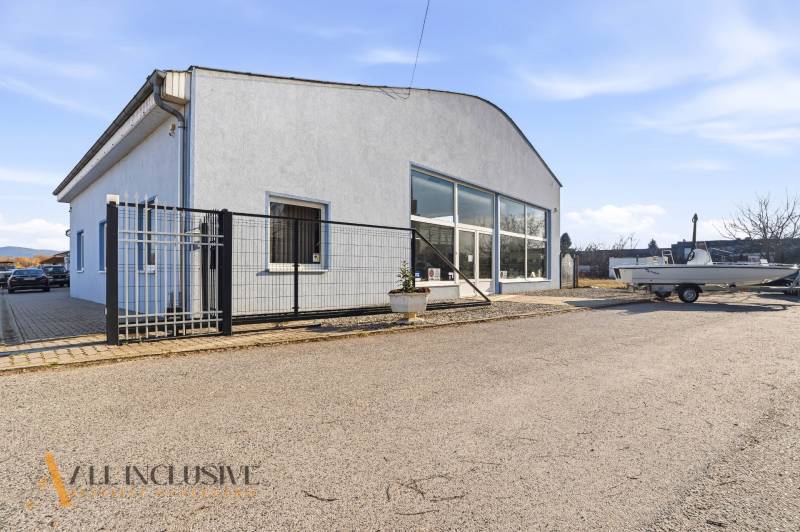 Üzlethelyiség Párkányban szürke homlokzattal, parkolóval és előtetővel.