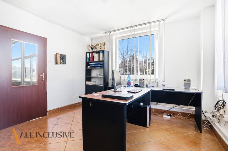 Iroda számítógéppel, polccal és ablakkal, függőleges redőnyökkel az üzleti helyiségben.