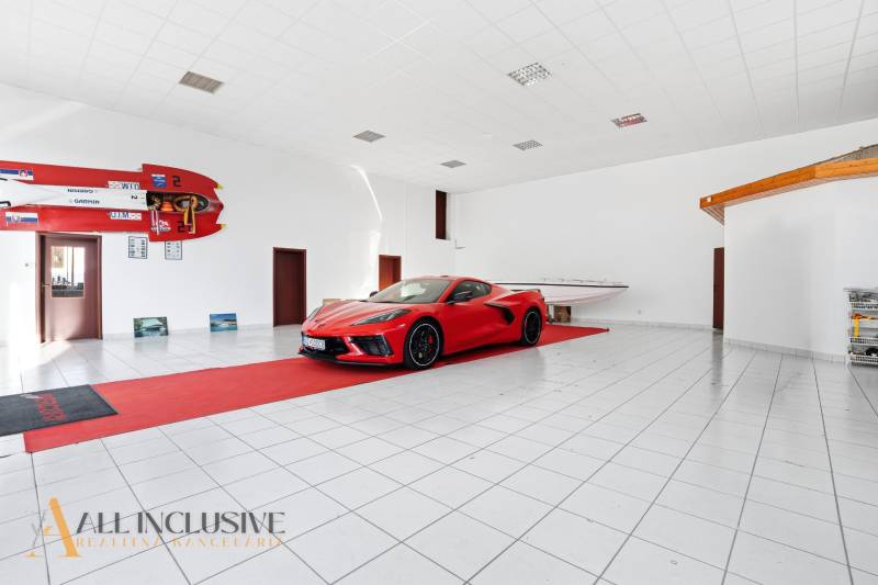 Az üzlethelyiség egy autót és egy hajót mutat be fehér padlóval és sportfelszereléssel.