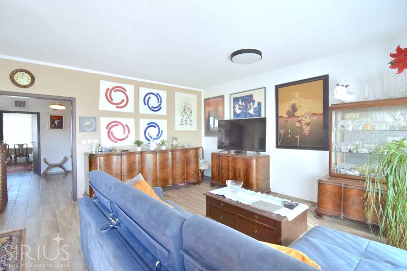 Nappali egy háromszobás lakásban fa dekor padlóval és stílusos bútorokkal.