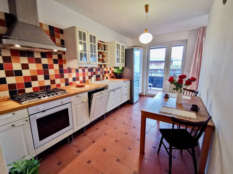 Konyha egy 4 szobás lakásban színes csempével, pulttal és asztallal virágokkal.