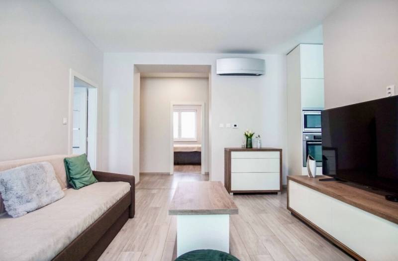 Nappali egy háromszobás lakásban, fa dekor padlóval és kényelmes kanapéval.