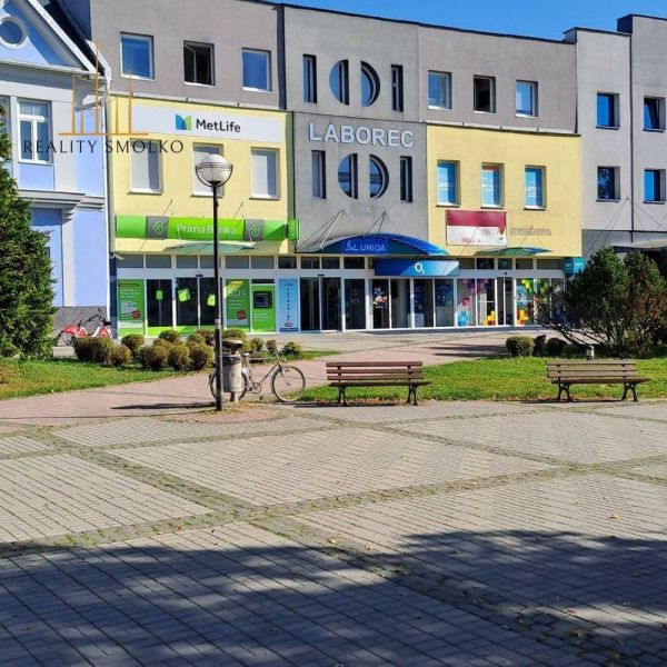 Üzlethelyiségek Homonnában bankokkal és biztosítással, ülőhely, oszlopnak támasztott kerékpár.
