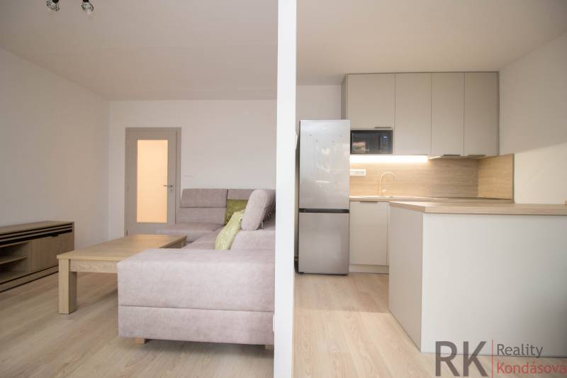 Nappali konyhával és fa dekoros padlóval egy háromszobás lakásban.