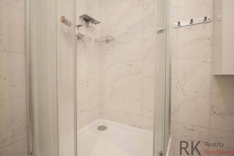 Zuhanyzó fehér márvány csempékkel a fürdőszobában egy háromszobás lakásban.