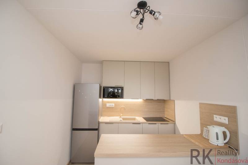 Konyha egy 3-szobás lakásban konyhabútorral, hűtőszekrénnyel és főzőlappal.